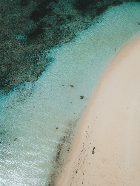 Aerial shot of the ocean waves hitting the sandy beach