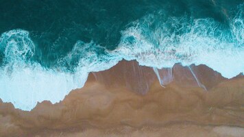aerial shot of sea waves hitting the sandy shore