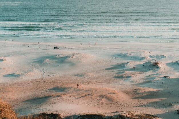 Aerial shot of people seen from distance on the beach during the sunset