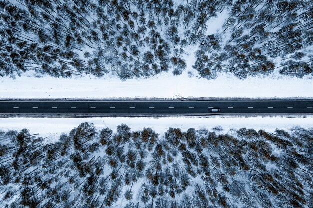 Aerial shot of a road in a forest covered in the snow during winter