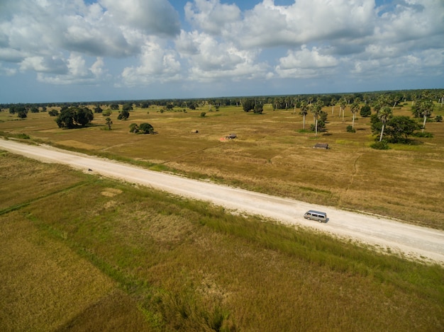 Aerial shot of a road surrounded by grass covered fields captured in Zanzibar, Africa