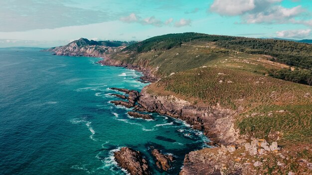 Aerial shot of rocky cliffs near a turquoise seascape