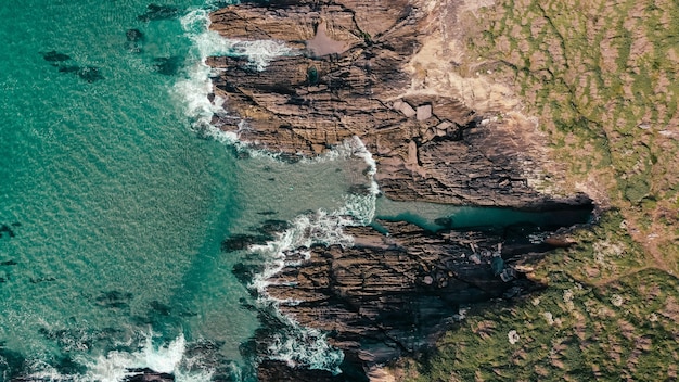 Aerial shot of rocky cliffs near a turquoise seascape