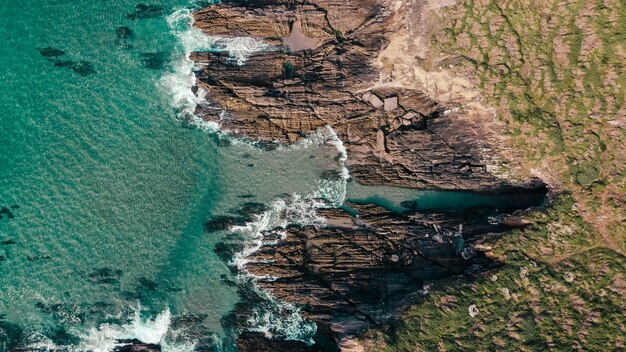 Aerial shot of rocky cliffs near a turquoise seascape