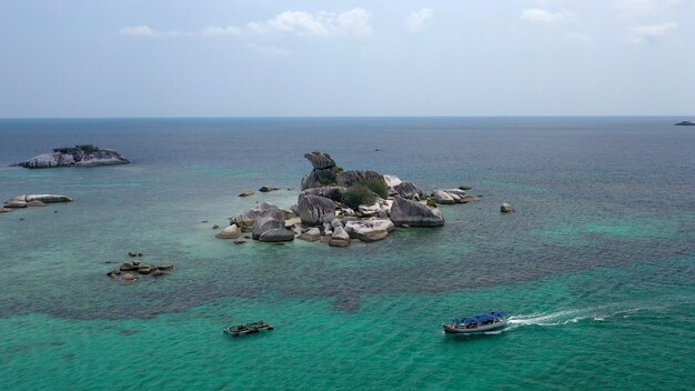 Aerial shot of a rocky island near a boat in the sea