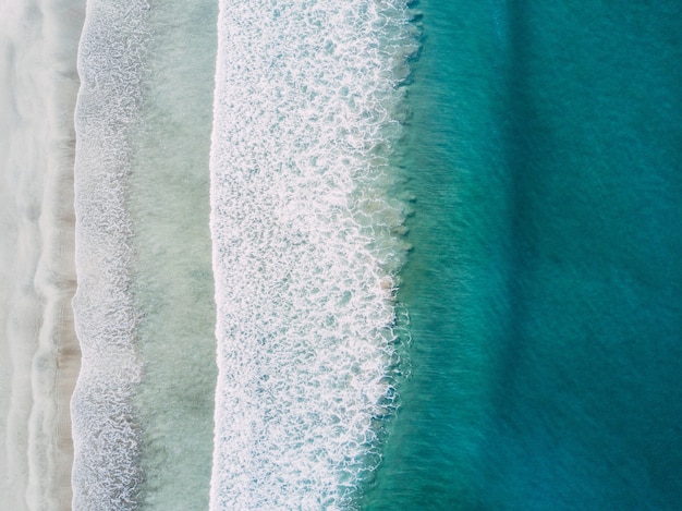 Aerial shot of sea waves hitting the shore at daytime