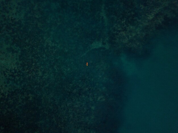 Aerial shot of the sea with a small kayak visible in the distance