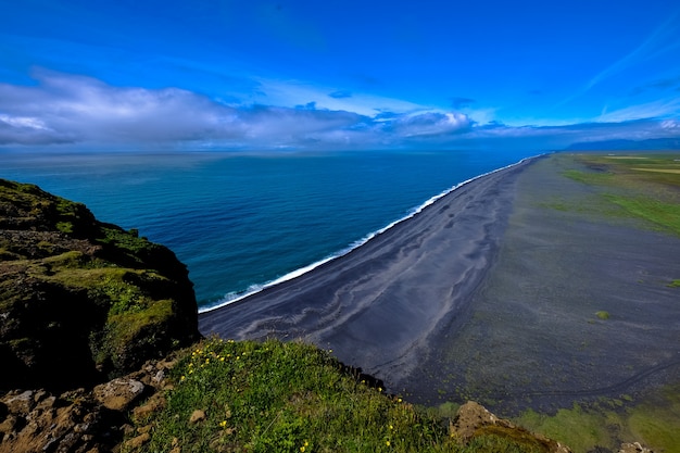 Aerial shot of shoreline near the mountain under a blue sky at daytime