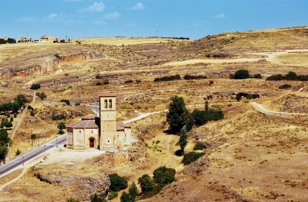 Aerial shot of a small tower next to a road in the yellow valley in Segovia, Spain