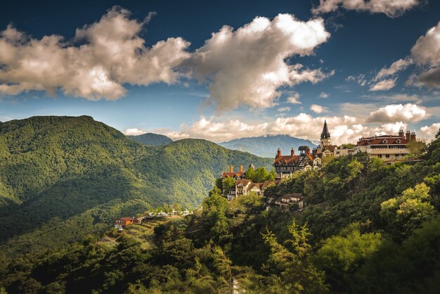 Aerial shot of a small village on the hill surrounded by forested mountains