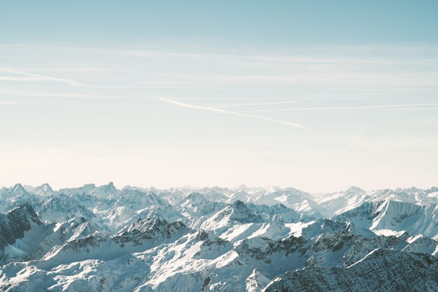 Aerial shot of snowy mountains under a beautiful sky at daytime