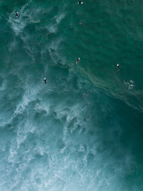 強い波が来るのを待って海でボードの上に敷設して泳いでいるサーファーの空中ショット