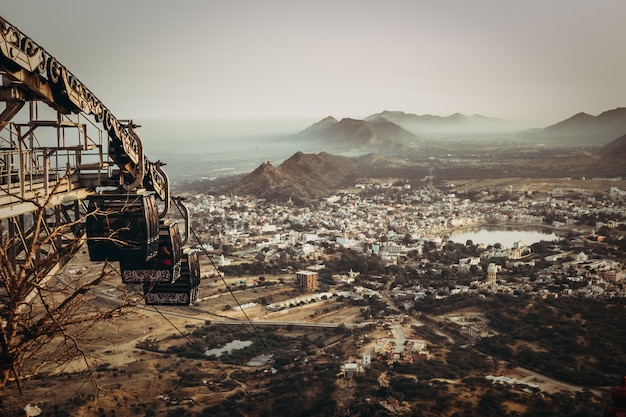 Aerial shot of a town in a valley with a lake and rocky mountains and an rusty abandoned ropeway