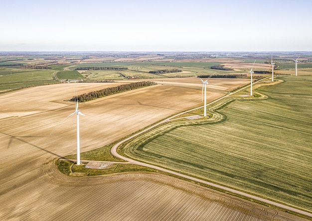 Аэрофотоснимок турбин на красивых зеленых полях возле вспаханных ферм