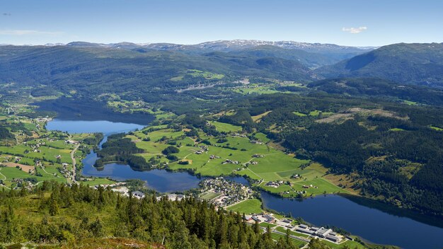 Aerial shot of Vossevangen municipality surrounded by greenery-covered mountains in Norway