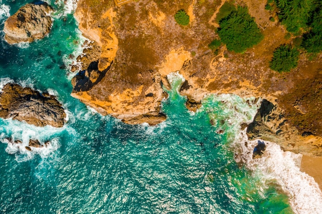 Воздушный снимок волнистого моря на фоне скал в дневное время