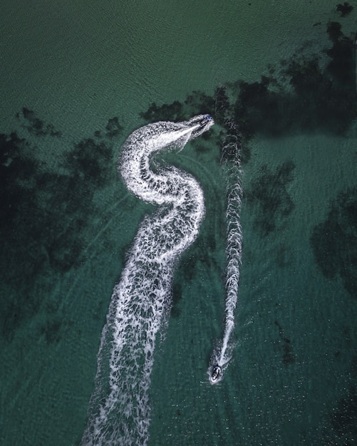 Free photo aerial shot of yachts cruising in the sea leaving splashing traces