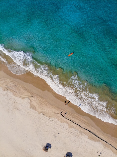 Aerial vertical shot of people on the beach shore at daytime