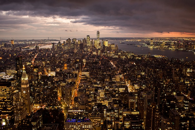 Aerial view of a beautiful cityscape with illuminated buildings and a sea under the storm clouds