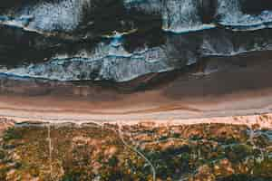 Free photo aerial view of the beautiful coastline with ocean waves crashing into the sandy beaches