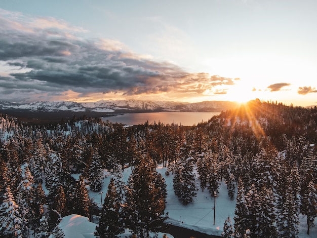 米国カリフォルニア州の雪に覆われた夕日に撮影された美しいタホ湖の空撮