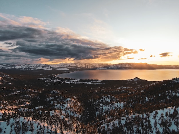 米国カリフォルニア州の雪に覆われた夕日に撮影された美しいタホ湖の空撮