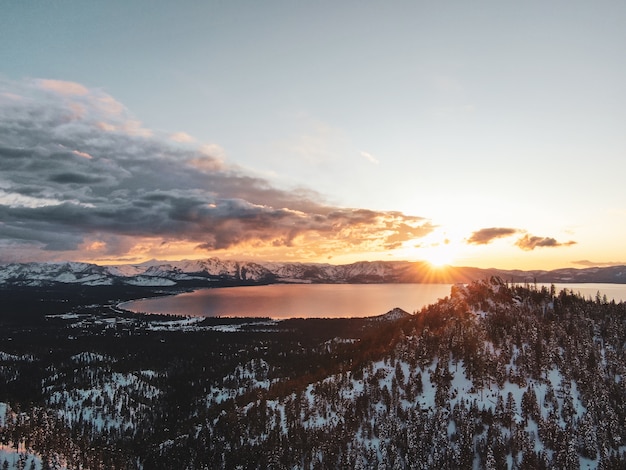 アメリカ、カリフォルニア州の雪に覆われた夕日に撮影された美しいタホ湖の空撮