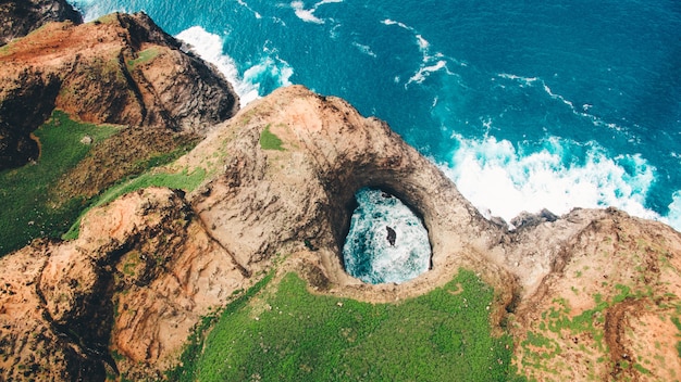 Free photo aerial view of beautiful openceiling sea cave on the na pali coast of kaua’i with greenery