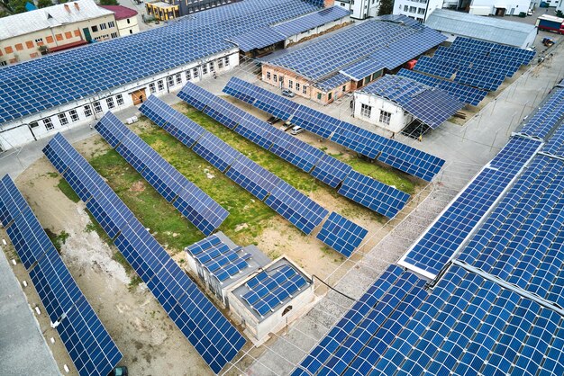 Aerial view of blue photovoltaic solar panels mounted on industrial building roof for producing green ecological electricity. production of sustainable energy concept.