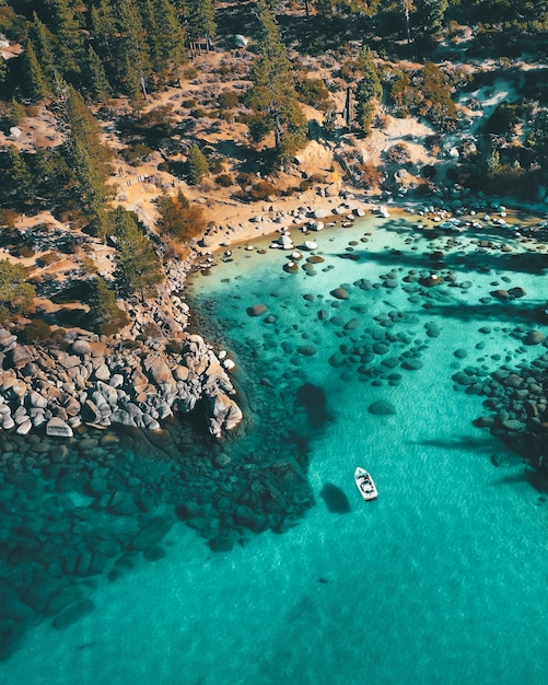 Вид с воздуха на лодку на воде на каменистом пляже
