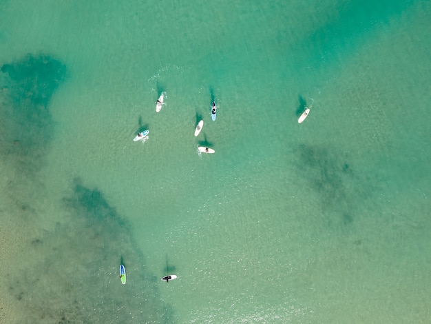 地中海​の​ターコイズ ブルー​の​澄んだ​海​で​スタンド アップ パドル​または sup を​練習する​人々​の​ド​ローン​による​空​撮