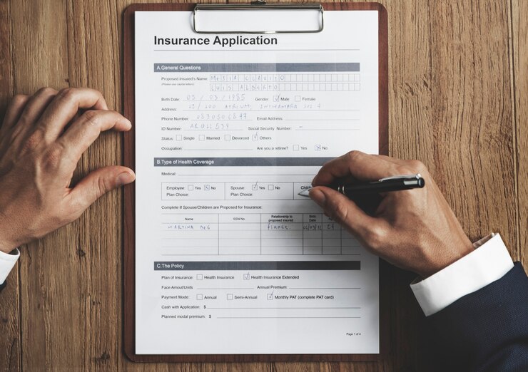 Free Photo aerial view closeup of hands filling insurance application form on wooden table