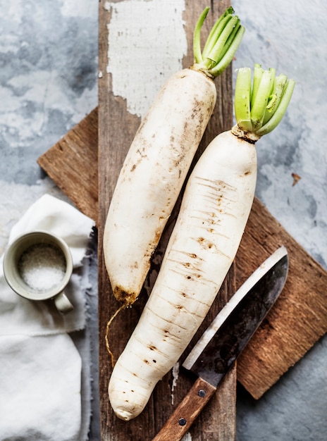 Aerial view of daikon radish on wooden cutboard with knife