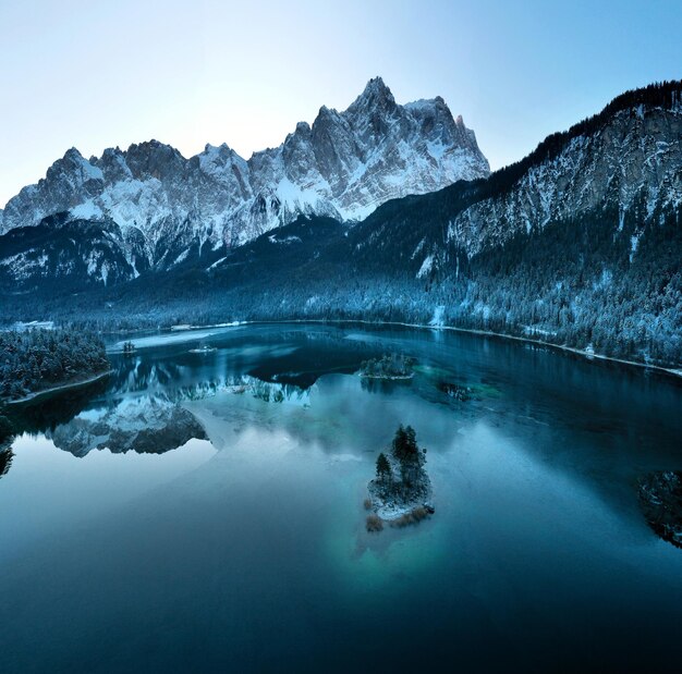 Aerial view of the frozen Eibsee river surrounded by trees covered with snow in Bavaria, Germany