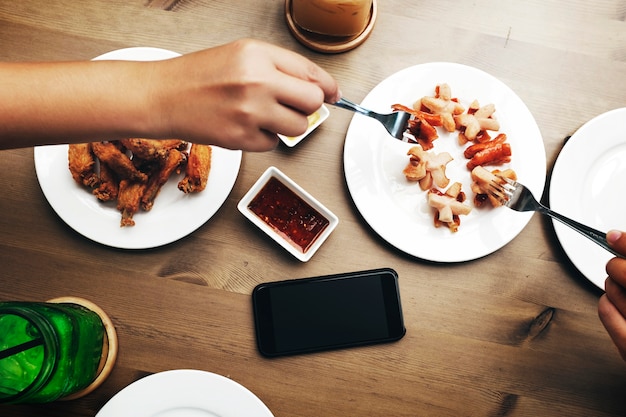 木製のテーブルに食べ物を得る手の航空写真