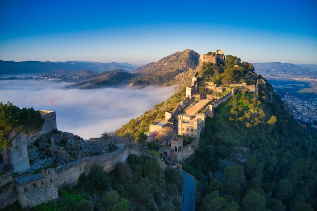 안개로 아름답게 덮인 언덕에 있는 중세 성의 공중 전망