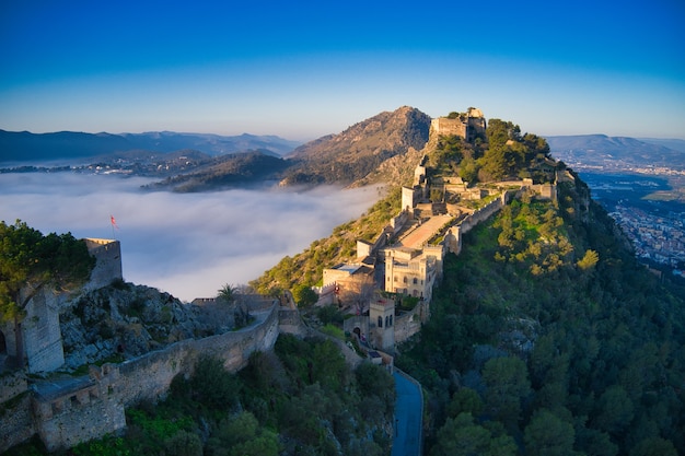 Aerial view of a medieval castle on a hill beautifully covered with fog