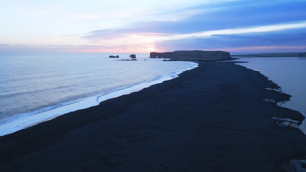 Бесплатное фото Воздушный вид на черный песчаный пляж с горами и большими камнями в исландии, красивые природные пейзажи на пляже рейнисфжара. исландский пейзаж с атлантическим океаном на береговой линии.