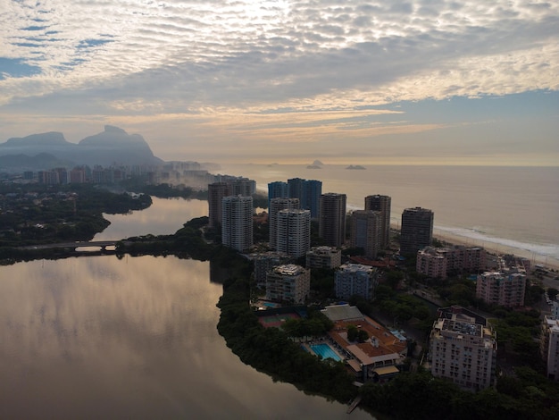 マラペンディラグーンの空撮。背景には、ブラジルのリオデジャネイロにあるバーハダチジュカビーチとペドラダゲヴェアのような丘があります。夜明け。晴れた日、雲があります。ドローンの写真。 Premium写真