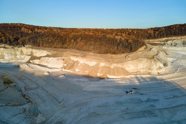 掘削機​と​ダンプトラック​を​備えた​建設業向け​の​石灰石​材料​の​露天掘り​採掘​現場​の​航空​写真