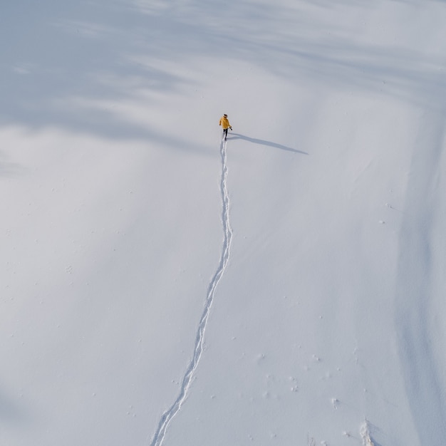 雪に覆われたフィールドを歩いている人の空撮