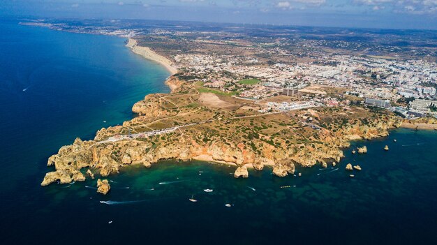 ポルトガル、ラゴスのポンタダピエダーデの空撮。ポルトガルのアルガルヴェ地方の険しい海辺の崖と水色の海の美しさの風景