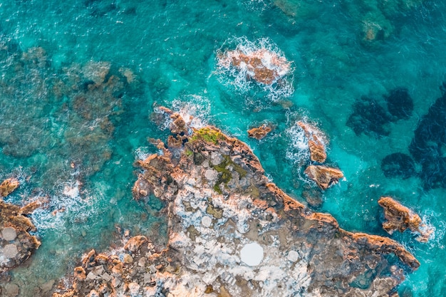 Aerial view of rocks under turquoise water