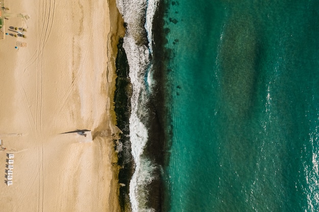 Foto gratuita vista aerea della sabbia che incontra l'acqua e le onde di mare