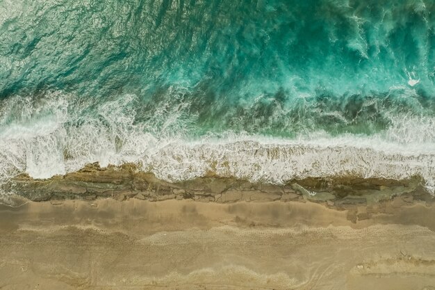 Aerial view of sand meeting the sea water and waves