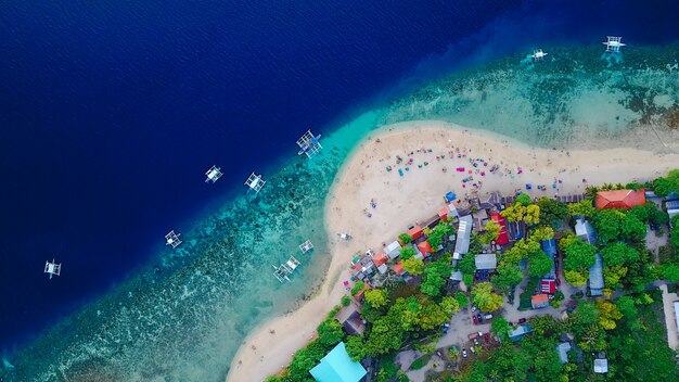 Вид с воздуха на песчаный пляж с туристами, плавающими в красивой чистой морской воде пляжа Сумилонского острова, приземляющегося возле Ослоба, Себу, Филиппины. - Увеличьте цвет обработки.