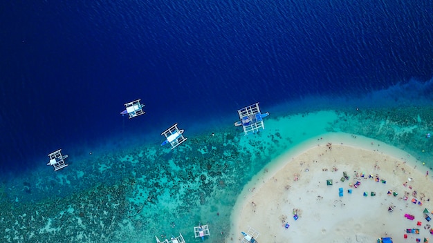 Вид с воздуха на песчаный пляж с туристами, плавающими в красивой чистой морской воде пляжа Сумилонского острова, приземляющегося возле Ослоба, Себу, Филиппины. - Увеличьте цвет обработки.