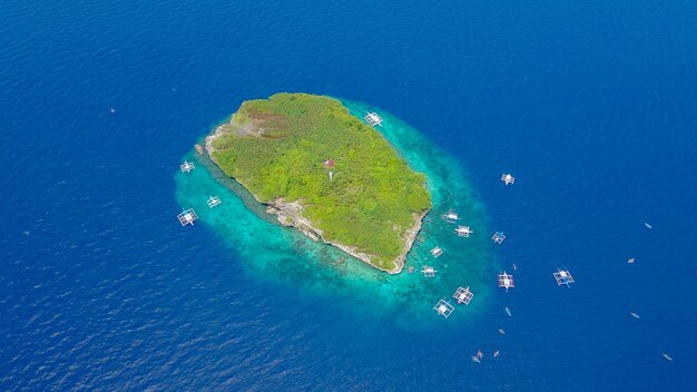 オシロス、セブ、フィリピンの近くに上陸するスミロン島のビーチの美しい透明な海の水で泳いで観光客と砂浜の航空写真。 - ブーストアップカラー処理。