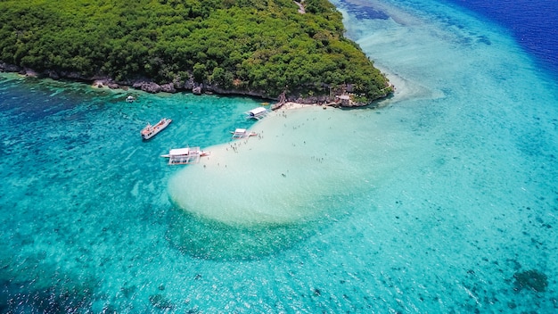 Aerial view of sandy beach with tourists swimming in beautiful clear sea water of the Sumilon island beach landing near Oslob, Cebu, Philippines. - Boost up color Processing.