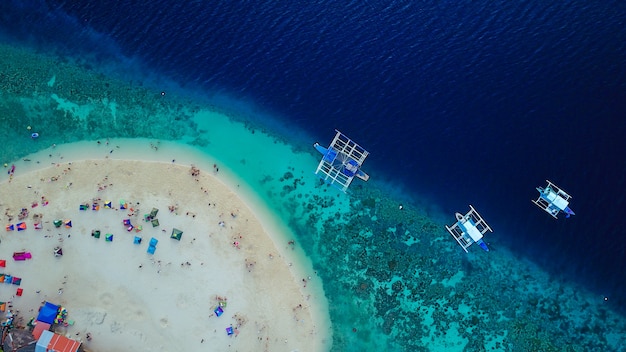 オシロス、セブ、フィリピンの近くに上陸するスミロン島のビーチの美しい透明な海の水で泳いで観光客と砂浜の航空写真。 - ブーストアップカラー処理。